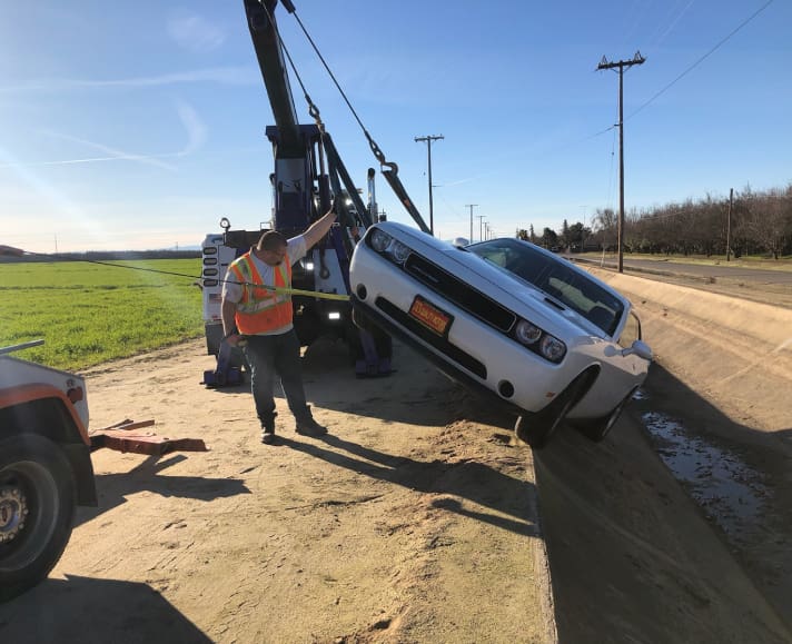 A tow truck is lifting the car off of it's flatbed.