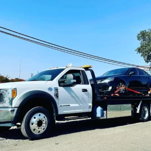 A white tow truck with a black car on the back