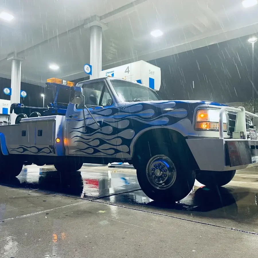 A white tow truck parked in the rain.