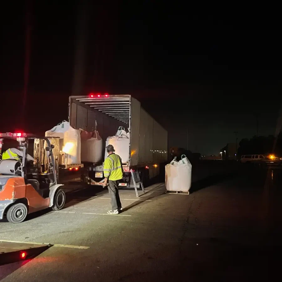 A man standing next to a truck at night.