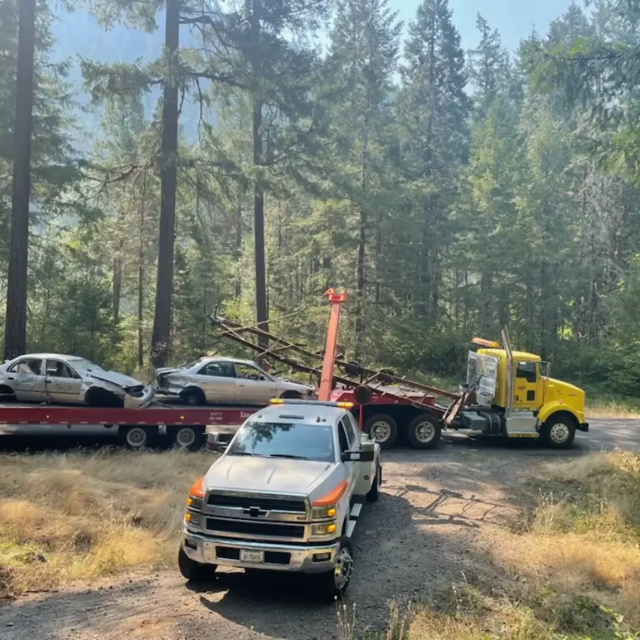 A truck is towing a car on the back of a trailer.