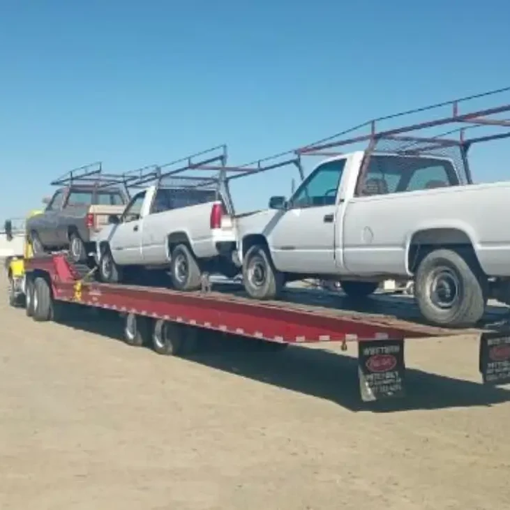 A tow truck is carrying two trucks and one truck has been pulled.